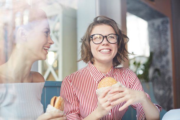 amiche-pranzando- al-fast-food-a-rischio-di-obesita-infantile-e-adolescenziale Giovani amiche che pranzano al fast food con un hamburger, a rischio di sviluppare una forma infantile e adolescenziale di obesità