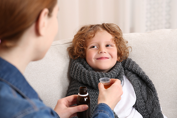Bambino che assume un antibiotico sotto forma di sciroppo grazie alla madre per la cura dello streptococco