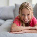 Bambina gioiosa sul divano di casa guarita dall’infiammazione del palato