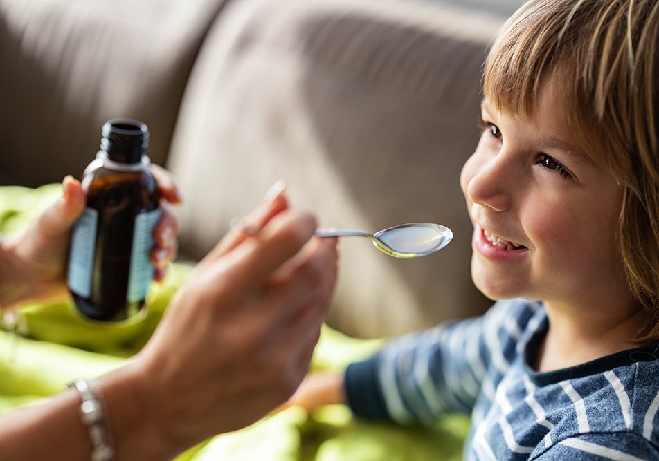 Bambino sorridente con infezione in corso che assume Augmentin sospensione orale per una pronta guarigione