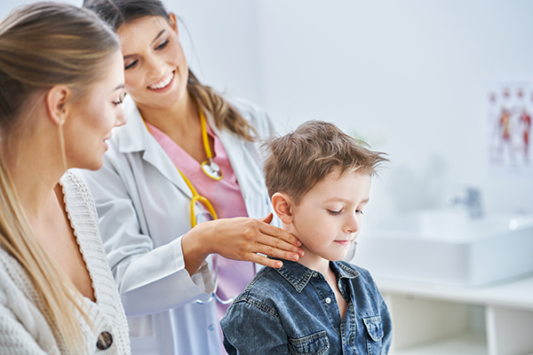 Bambino alla visita pediatrica per individuare i sintomi dello streptococco, come i linfonodi ingrossati