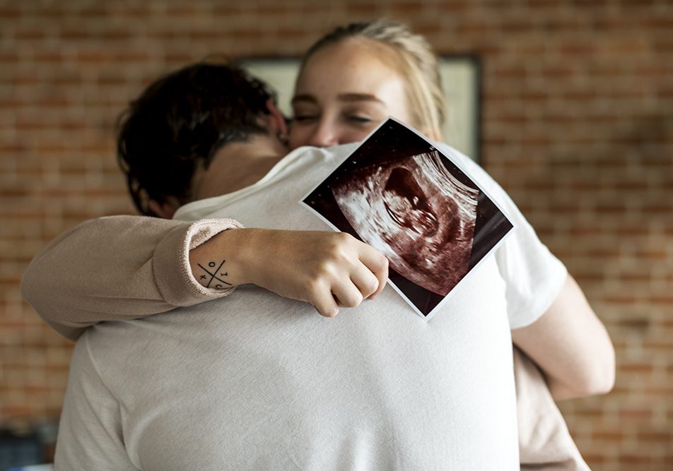 coppia-abbracciandosi-con-ecografia-dopo-sintomi-gravidanza-primi-giorni Coppia che si abbraccia emozionata, in cui la donna tiene in mano un’ecografia effettuata appena dopo i primi giorni dai sintomi della gravidanza