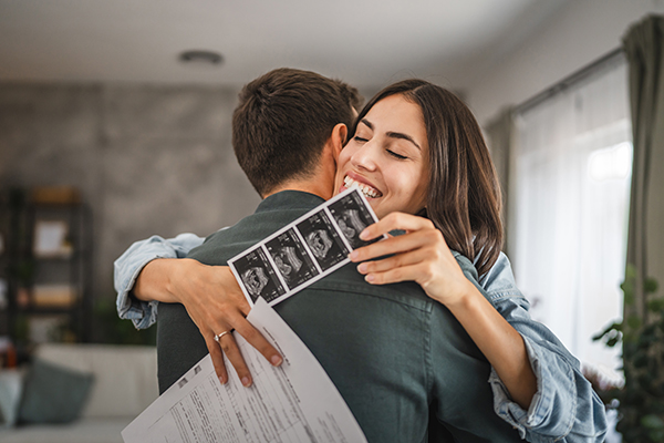 Coppia abbracciata con esiti di un esame di cui usufruiscono attraverso le esenzioni per gravidanza