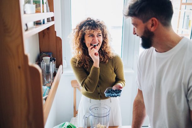 Giovane coppia in cucina che prepara uno spuntino salutare con mirtilli per alleviare i sintomi dell’Helicobacter pylori