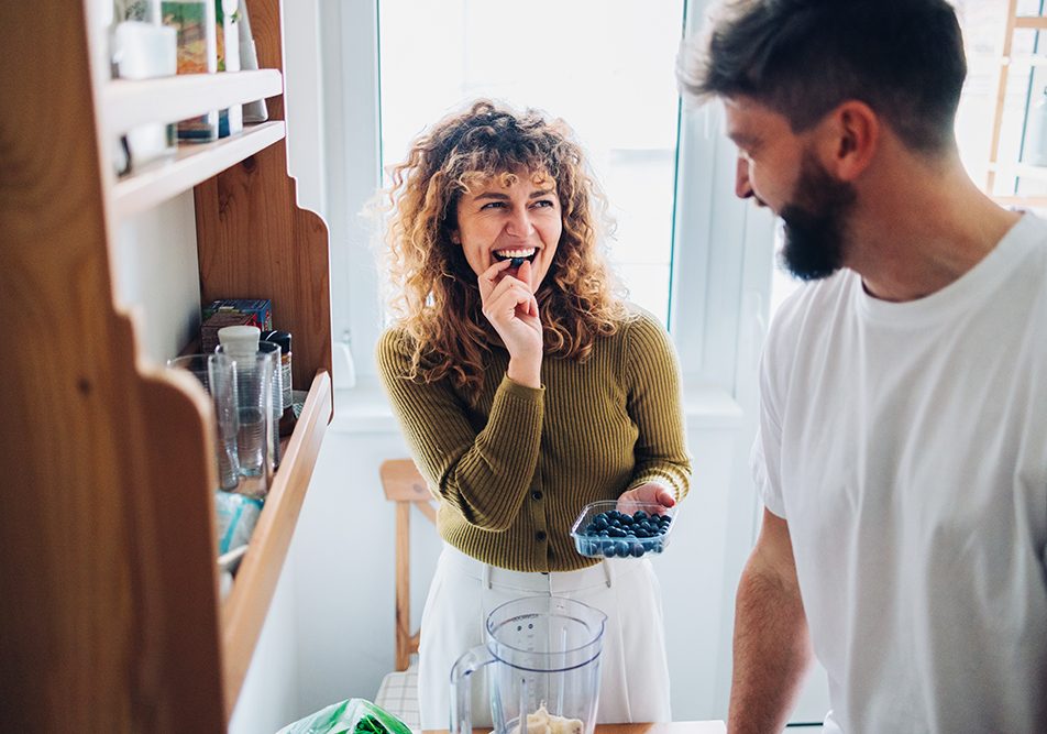 Giovane coppia in cucina che prepara uno spuntino salutare con mirtilli per alleviare i sintomi dell’Helicobacter pylori