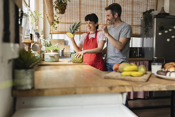 Coppia di fidanzati in cucina che taglia un ananas, un rimedio naturale per la cura dell’Helicobacter pylori
