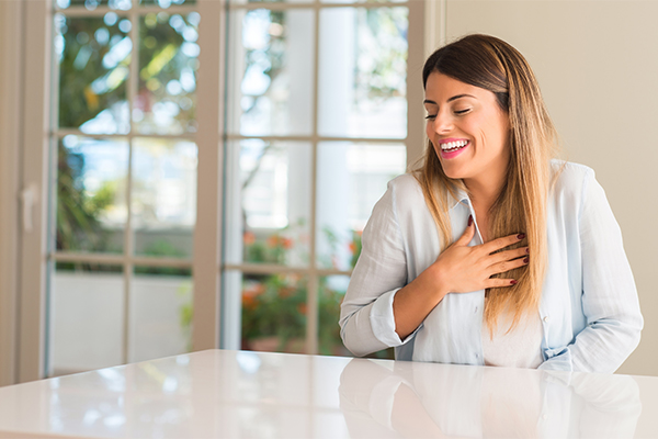 Donna seduta al tavolo di casa che avverte sintomi di problemi ai polmoni