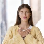 Giovane donna con sintomi di fitte al cuore si tocca il petto