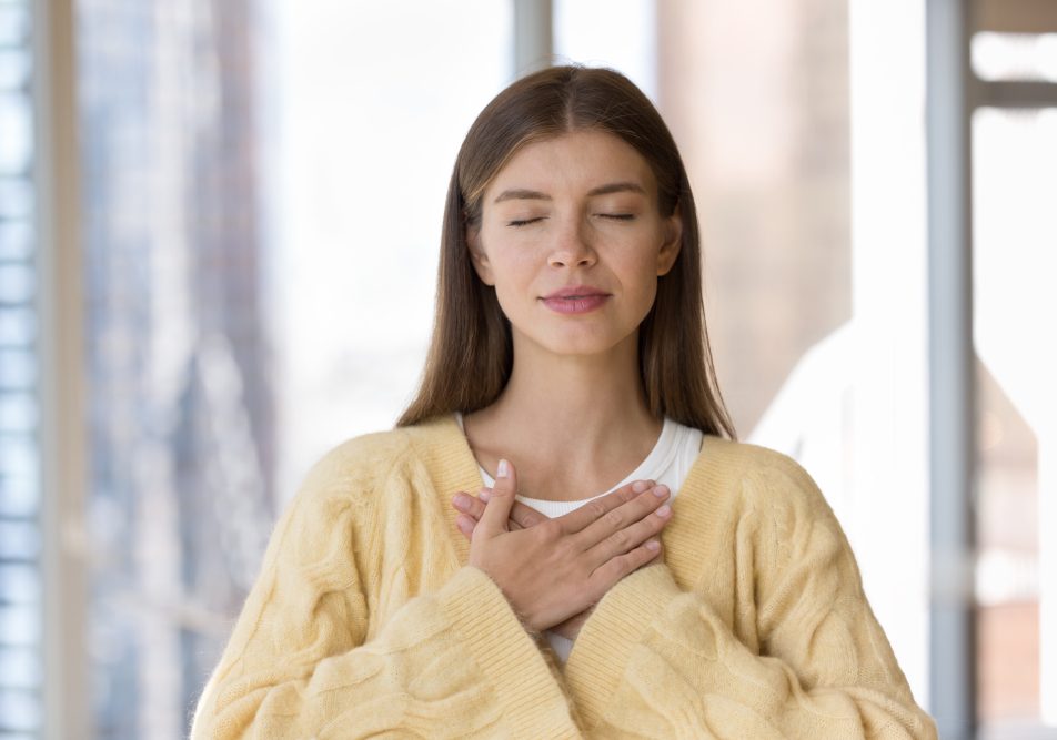 Giovane donna con sintomi di fitte al cuore si tocca il petto