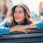 Donna sorridente al parco cittadino, che conduce uno stile di vita sano ed equilibrato per la prevenzione delle bolle sul palato
