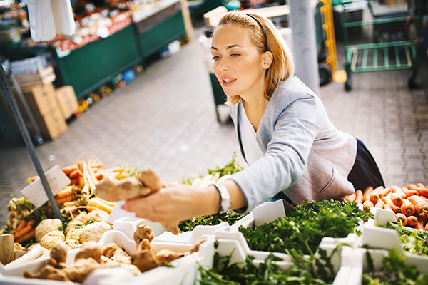 Donna che cura la gastrite attraverso un’alimentazione sana acquista al mercato dello zenzero
