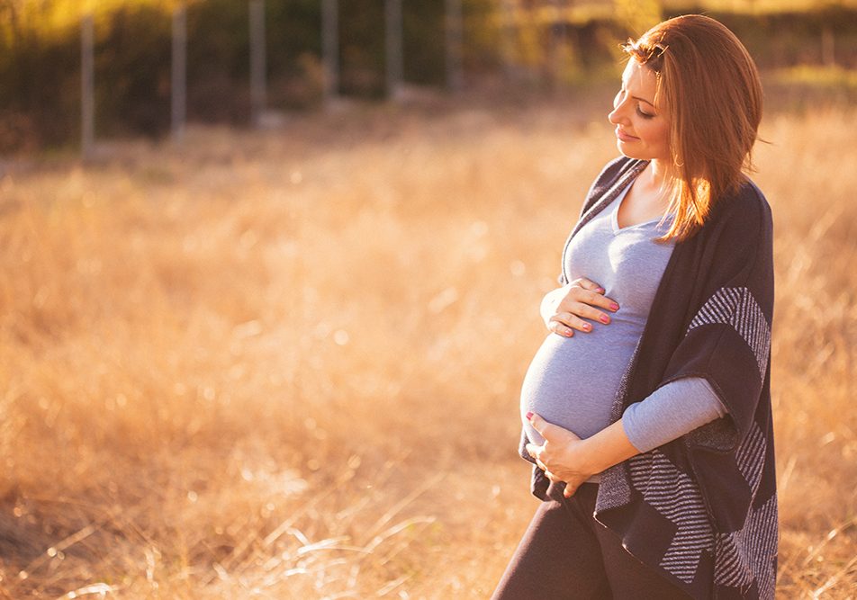 Donna in gravidanza con esenzione M50 rilassata nella natura mentre aspetta la nascita del suo piccolo