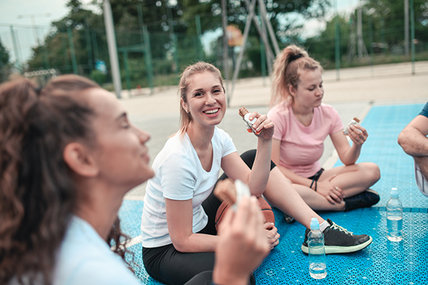 Giovane donna che previene la salute delle arterie coronarie praticando attività fisica insieme ad un gruppo di coetanee, durante una pausa dall'allenamento