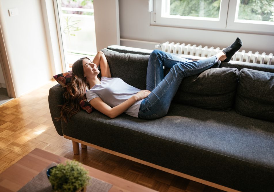 Giovane donna stesa sul divano che presenta sintomi di ematuria