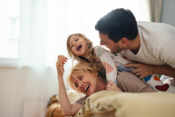 Famiglia in un momento di gioia nel letto di casa guarita dai sintomi della dermatite perianale