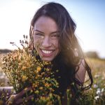 Giovane donna sdraiata in un campo di fiori dopo la guarigione dai sintomi dell’herpes genitale