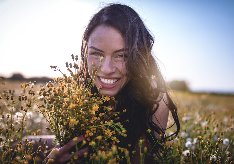 Giovane donna sdraiata in un campo di fiori dopo la guarigione dai sintomi dell’herpes genitale