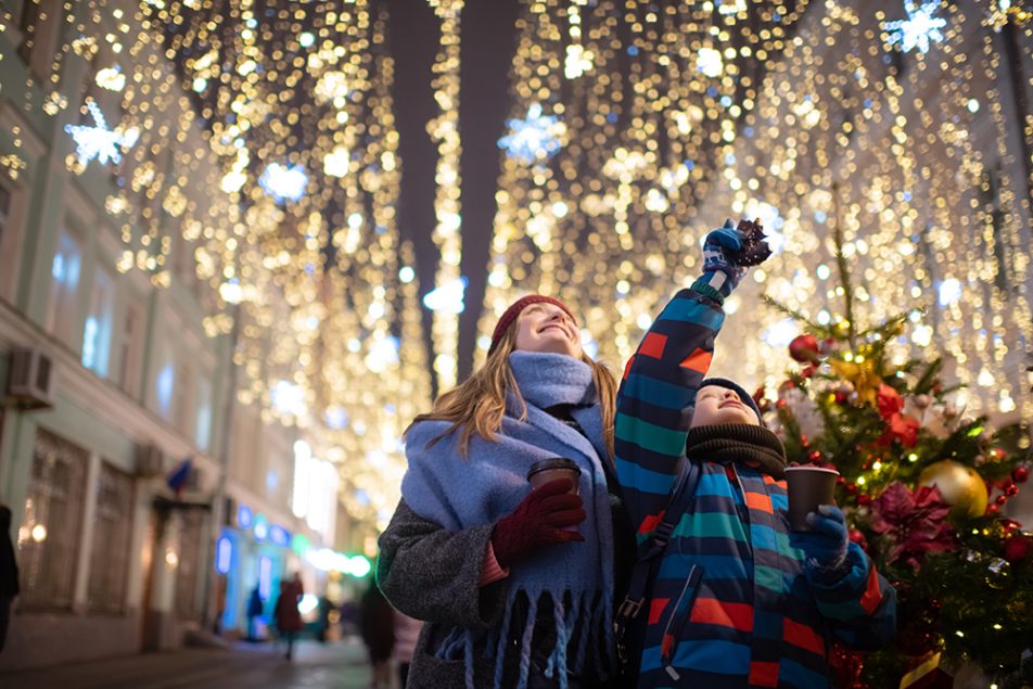 Madre e figlio che si divertono visitando un mercatino di Natale in seguito ad una ricerca su dove andare a Natale in Italia