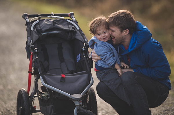 Padre che abbraccia affettuosamente il suo bambino fuori dal passeggino, sofferente di una patologia con cui ha diritto all’esenzione ticket