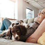 Giovane donna sul divano con cane che ha perdita del pelo
