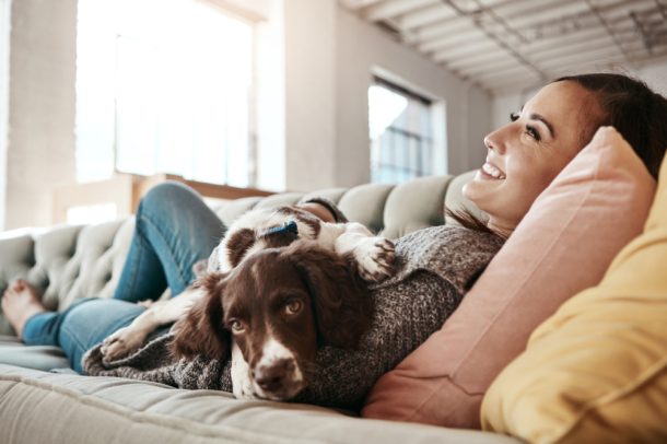 perdita-del-pelo-cane Giovane donna sul divano con cane che ha perdita del pelo