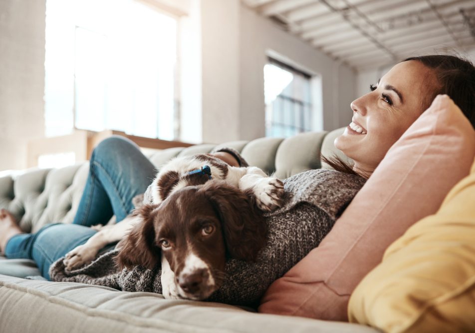 Giovane donna sul divano con cane che ha perdita del pelo