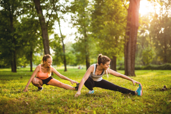 Ragazze al parco svolgono esercizi di stretching per prevenire i crampi alle gambe