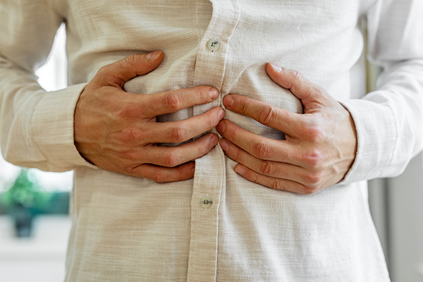 Uomo con dolore allo stomaco che si tocca la pancia, un primo sintomo comune di Helicobacter pylori