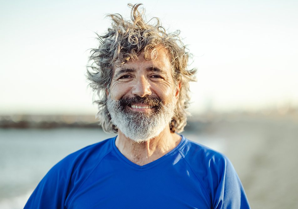 uomo-maturo-prevenzione-streptococco-con-attivita-fisica Uomo maturo sorridente dopo una camminata sulla spiaggia che previene lo streptococco grazie all’attività fisica all’aria aperta