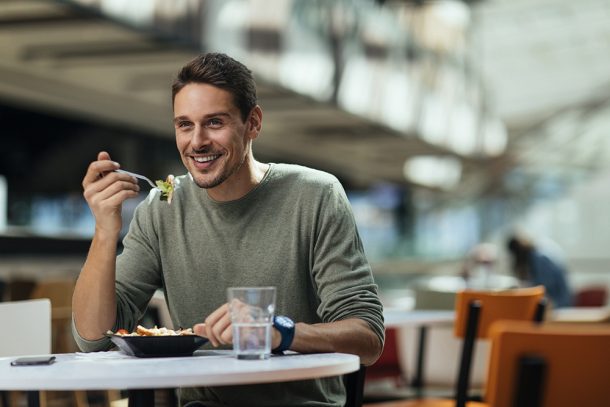 Uomo che mangia un primo piatto durante la pausa pranzo, alla ricerca di rimedi naturali per il bruciore di stomaco
