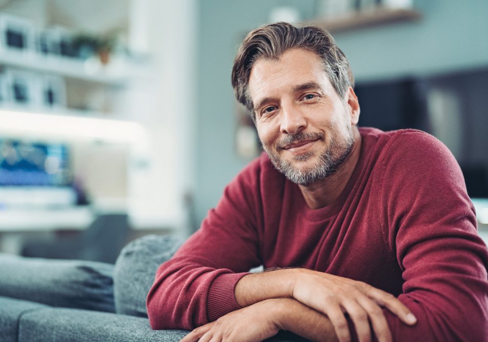 Uomo sopra i 50 anni nel proprio salotto, che soffre di ingrossamento della prostata