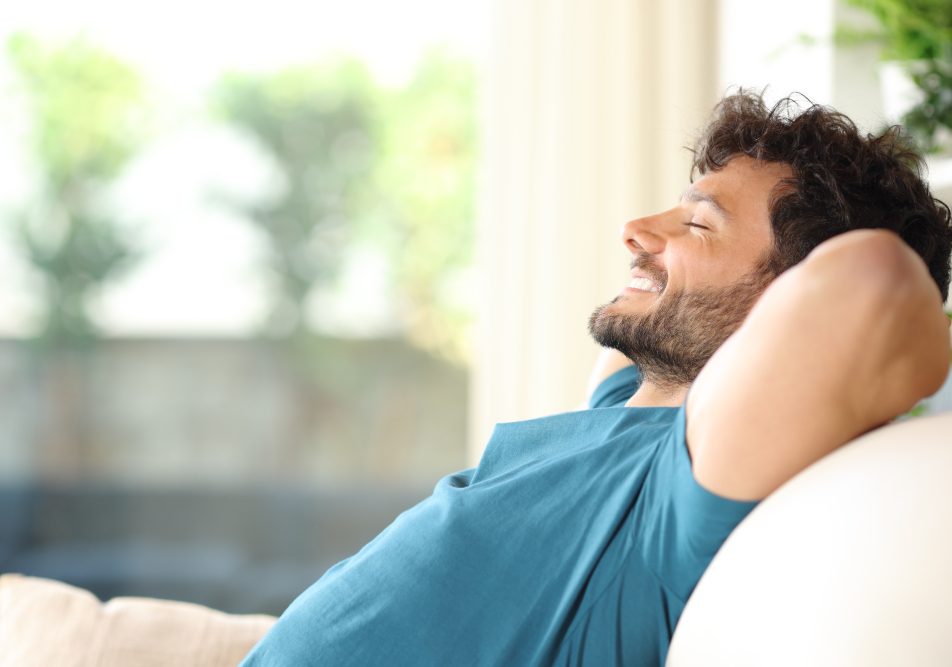 Giovane uomo sul suo divano di casa rilassato per i benefici della laserterapia