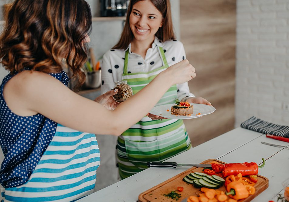 Amiche in cucina che indossano il grembiule e preparano una ricetta ricca di Omega 3 con tonno e semi di lino