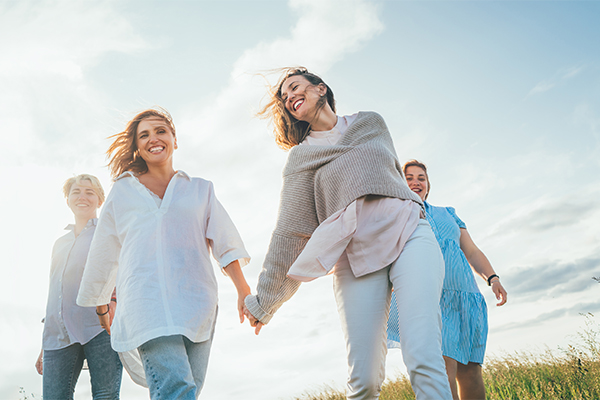 Amiche donne che passeggiano solidariamente al parco tendendosi per mano, superando l’ansia del dolore al petto