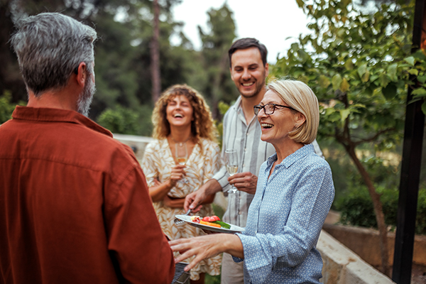 Gruppo di amici di diversa età, di cui alcuni con pancreatite cronica, che si godono una cena insieme in giardino