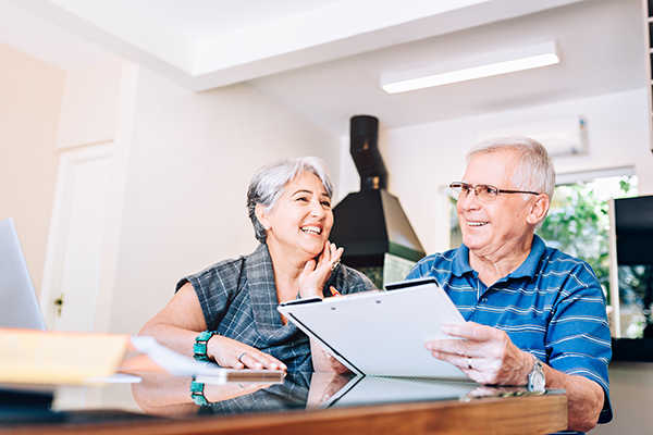 Coppia senior che pianifica le future visite con l’esenzione E03, seduti alla scrivania in uno studio medico informale e familiare