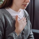 Giovane donna che soffre di reflusso gastroesofageo si porta la mano al petto