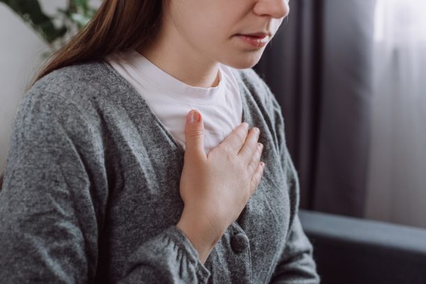 Giovane donna che soffre di reflusso gastroesofageo si porta la mano al petto