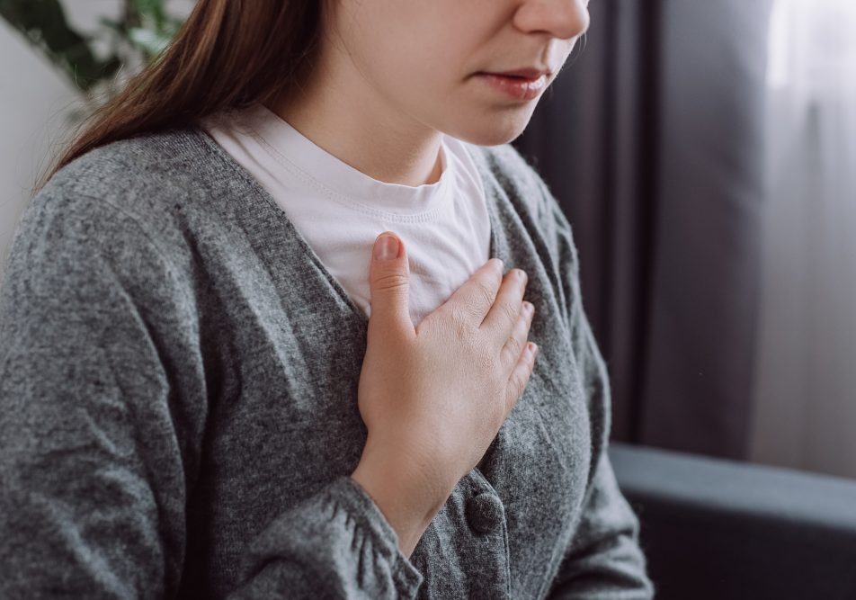 Giovane donna che soffre di reflusso gastroesofageo si porta la mano al petto