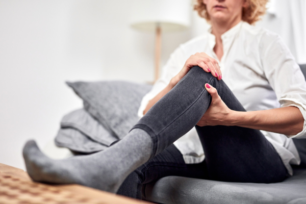 Donna seduta sul divano si tocca le gambe gonfie uno dei sintomi dello scompenso cardiaco