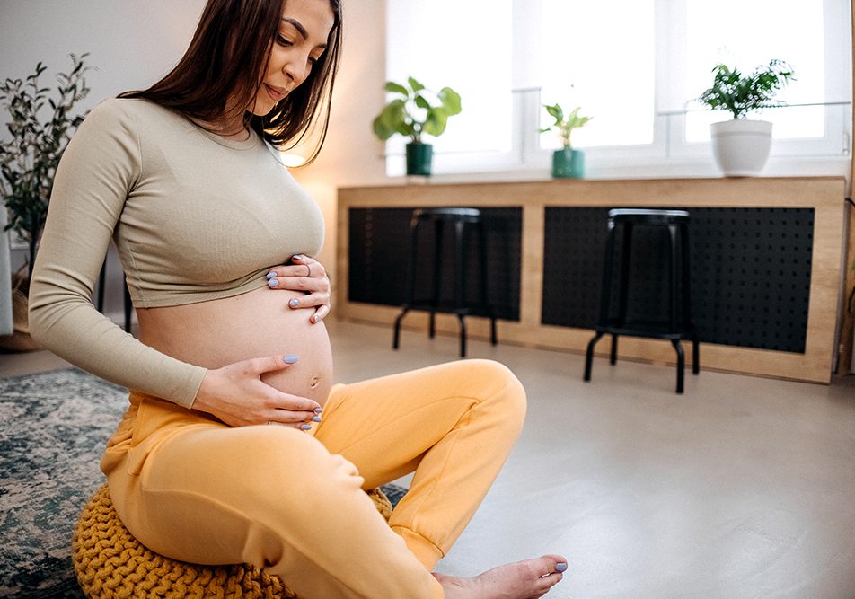 Donna incinta, con le mani sulla pancia, che si prende cura del dolore alle gengive attraverso pratiche di relax in casa