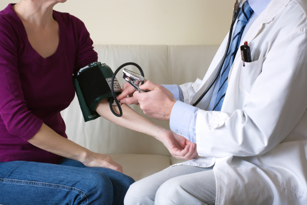 Medico misura pressione alla paziente che ha fatto esame di coronarografia
