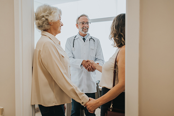 Donna che porta la madre anziana all’appuntamento medico grazie all’esenzione C01, presentandosi al dottore
