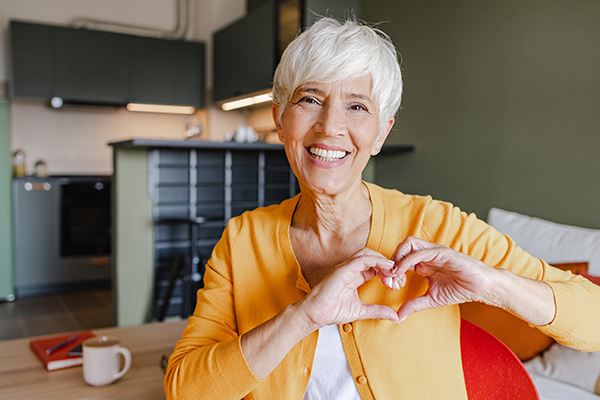 Donna senior che fa il gesto del cuore e che si prende cura della salute delle sue arterie coronarie
