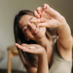 Donna sorridente nel confortevole salotto di casa che tiene in mano un integratore con Omega 3