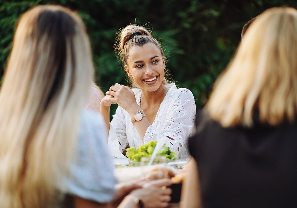 Giovane donna che soffre di pancreatite che si gode un pranzo insieme alle amiche all’aria aperta