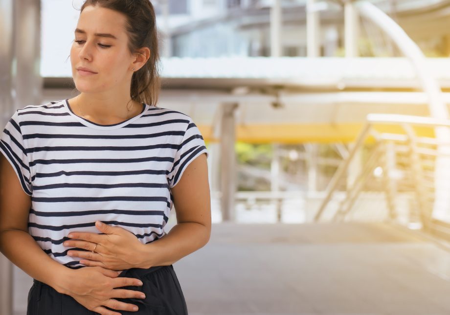 Giovane donna si tocca l'addome per sintomi pancreatite