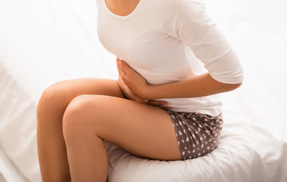 gonfiore-addominale-cause Giovane donna seduta sul letto si tiene la pancia cercando di capire le cause del suo gonfiore addominale