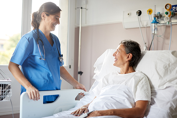 Infermiera che conforta una paziente sdraiata a letto in ospedale dopo un intervento di medicina rigenerativa