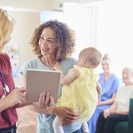 Giovane madre che consulta il personale della reception dello studio medico, in possesso dei requisiti per l’esenzione E03 per la figlia